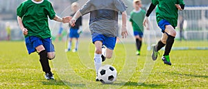 Boy Kicking Soccer Ball. Running Soccer Football Players. Five Junior Footballers on Duel. Football Grass Field and Soccer Stadium