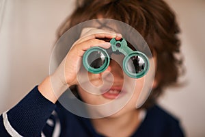 Boy, kid and binocular with toys and playing, closeup of fun and innocent with search or surveillance. Investigate