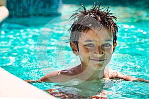 Boy kid child eight years old inside swimming pool portrait happy fun bright day.