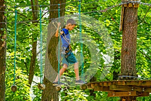 Boy kid enjoying activity in a climbing adventure park on a summer day
