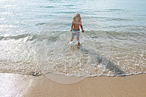 Boy kid jumping in sea waves. Jump by water sea splashes. Summer kids vacation.