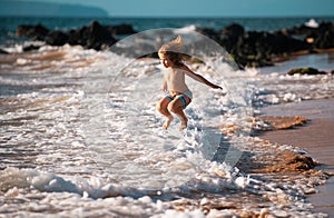 Boy kid jumping in sea waves. Jump by water sea splashes. Summer kids vacation.