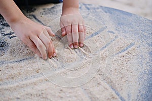 Boy kid playing with sand on the playground, the concept of the development of fine motor skills, tactile sensations, creativity,