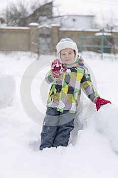 Boy kid playing in the snow. Baby playing with snow in winter. Little toddler boy in blue jacket and colorful hat catching