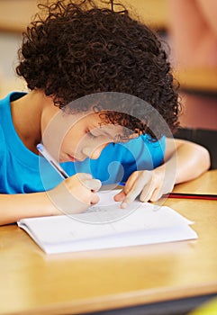 Boy kid, school and writing test in classroom with focus, concentration or thinking for education goals. Male child