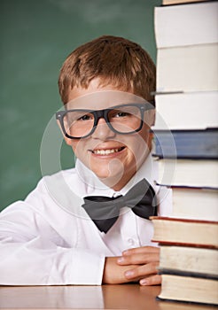 Boy kid, smile and portrait with books, classroom and learning for exam, assessment and studying for knowledge. Student