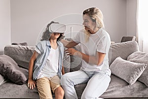 boy kid wearing virtual reality headset with his mother vr glasses in living room at home having fun
