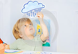 Boy in kindergarten class hold weather rain card