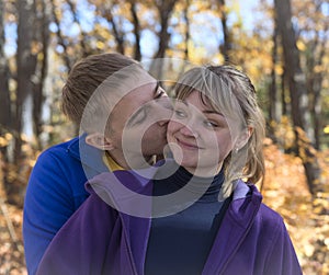 Boy kissing girl in autumn forest