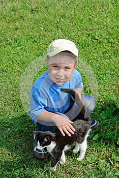 Boy with a kitten on a green grass