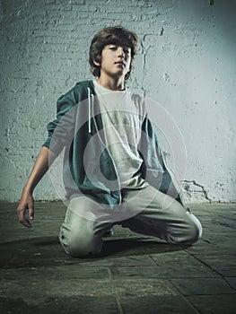 Boy kneeling on the ground in a defiant pose in front of the camera.