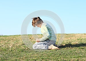 Boy kneeling on meadow photo