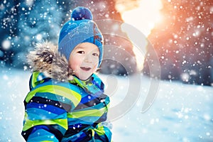 Boy in knitted hat, gloves and scarf outdoors at snowfall