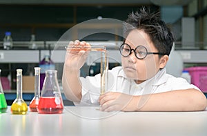 Boy in lab coat making experiment with test tube