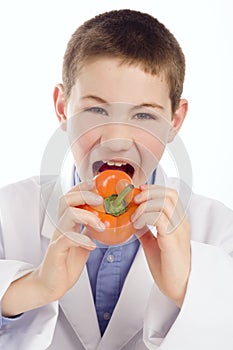 Boy in lab smock eating a pepper