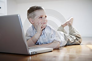 Boy with laptop computer laying down on the floor