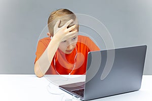 A boy with a laptop for online training grabbed his head