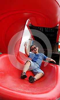 Boy laughing and sliding down on a spiral slide