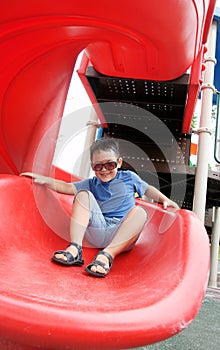 Boy laughing and sliding down on a spiral slide