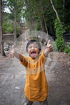 A boy laughs and shows thumbs up at the camera
