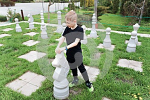 Boy on the lawn with the huge chess pieces picked up the horse and moved it one move further