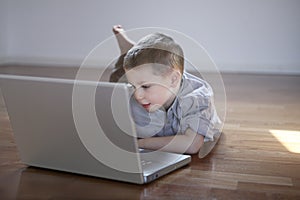 Boy laying down on the floor with laptop computer