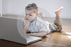 Boy laying down on the floor with laptop computer