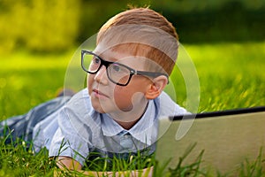 Boy laying on grass in the park with laptop