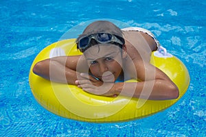 Boy laying on rubber ring in pool