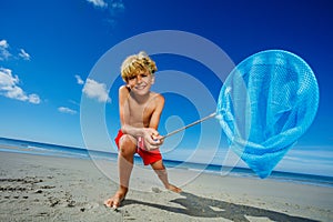 Boy lean holding butterfly net catching critters on beach