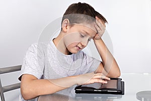 Boy leaned his head on the table on a Tablet PC