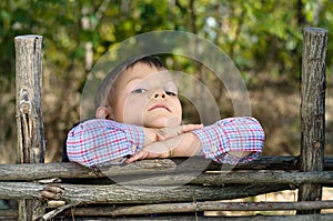 Boy Leaning on Arms on Top of Wooden Fence