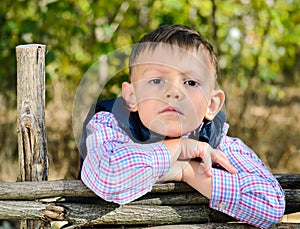 Boy Leaning on Arms on Top of Wooden Fence