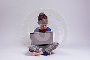 Boy learning with a laptop while sited on the floor