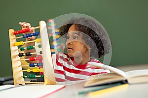 Boy learning mathematics with abacus in a classroom