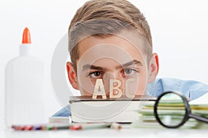 Boy with learning supplies reading abc book, education concept