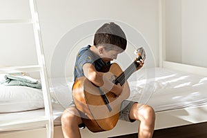 Boy learning to play acoustic guitar. Boy is practicing acoustic guitar in his room