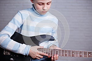 Boy learning to play an electric guitar. Music, hobby and leisur