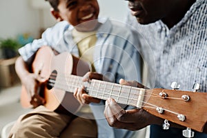 Boy learning to play guitar with teacher