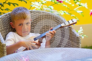 Boy learning to play the kid`s guitar