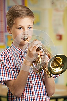 Boy Learning To Play Trumpet In School Music Lesson