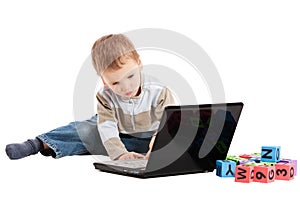 Boy learning to read with kids blocks and computer