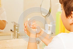 Boy learning to wash hands with soap and water