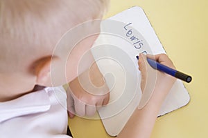 Boy learning to write name in primary class photo