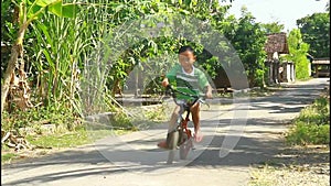 A boy learns to ride a bicycle without a safety helmet
