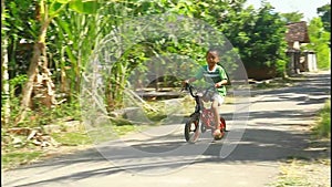 A boy learns to ride a bicycle without a safety helmet