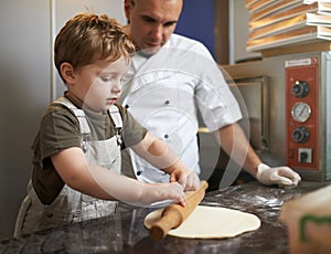 Boy learns to roll out pizza dough