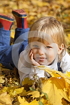 boy in leaves of autumn lies