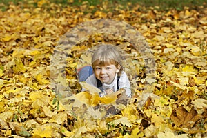 boy in leaves of autumn lies