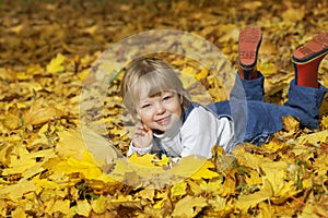 boy in leaves of autumn lies